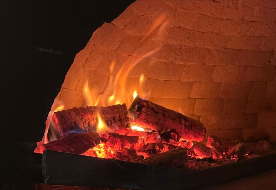 Brinnande ved och glöd i Donna Ginas vedugn